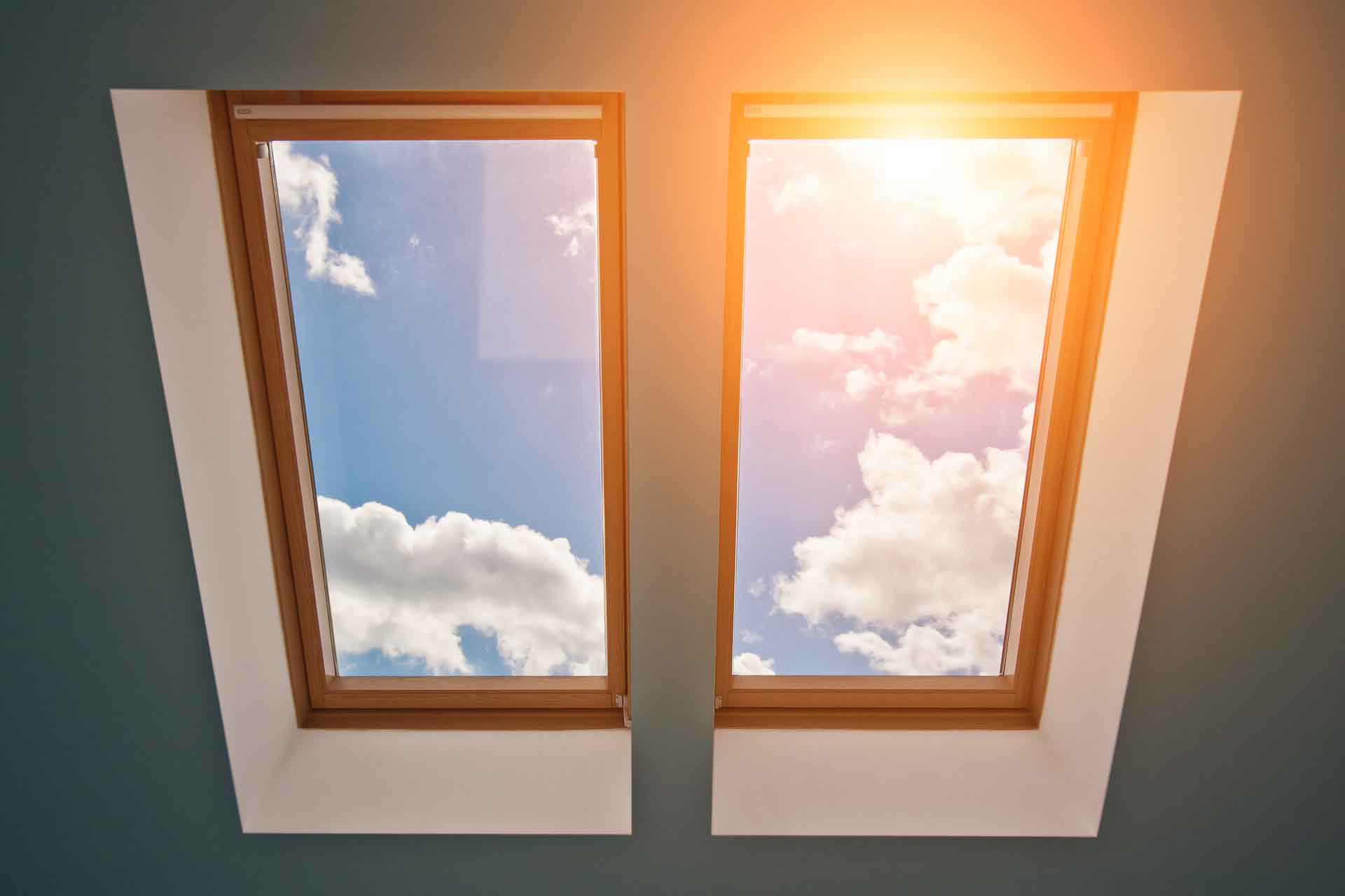 View of the sky and clouds from the window on the roof, sunlight through the attic window, light in the house, skylights